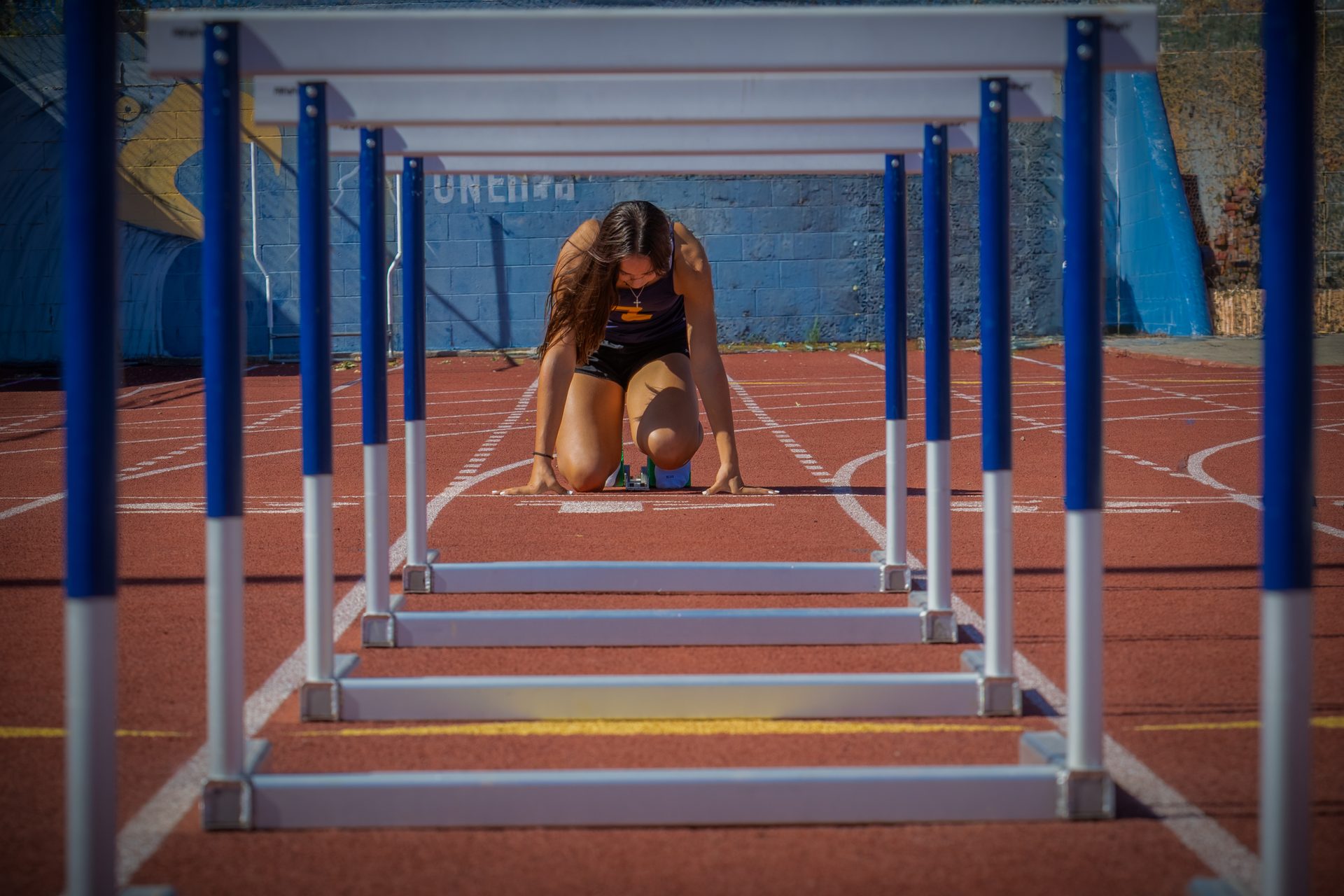 Athlete set in the blocks viewed through a tunnel of hurdles