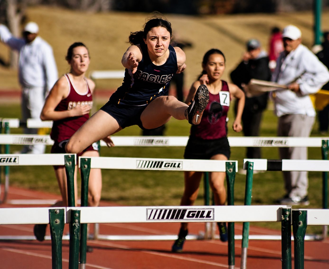 Lady Eagle clearing a hurdle at full extension during a dual meet
